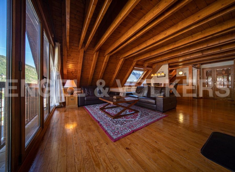 This stunning chalet boasts a spacious open-plan living area with high wooden beamed ceilings and large windows offering breathtaking views.