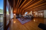 This stunning chalet boasts a spacious open-plan living area with high wooden beamed ceilings and large windows offering breathtaking views.