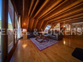 This stunning chalet boasts a spacious open-plan living area with high wooden beamed ceilings and large windows offering breathtaking views.