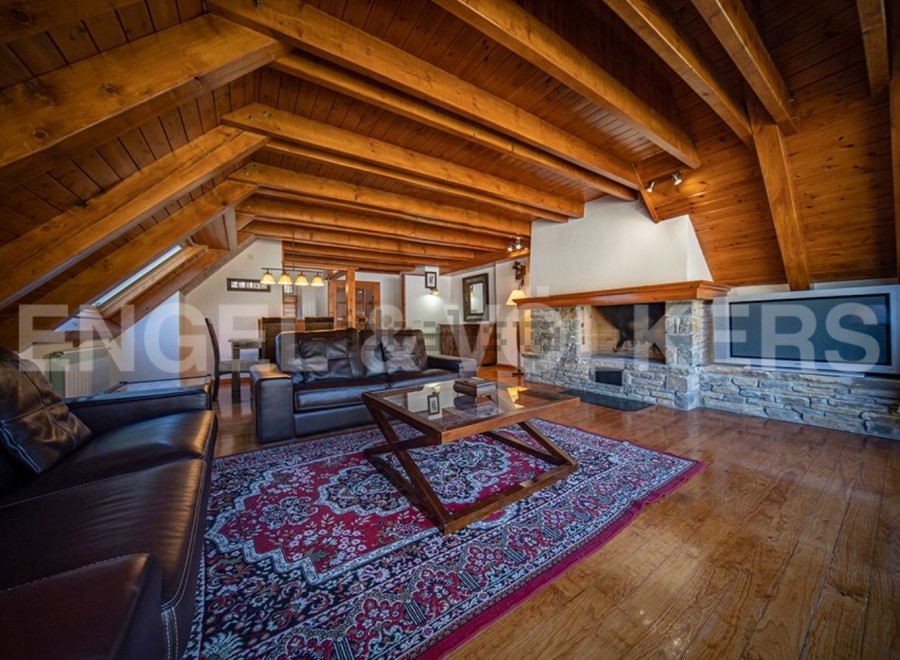 This stunning chalet boasts a spacious open-plan living area with exposed wooden beams, a cozy fireplace, and large windows offering ample natural light.