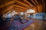 This stunning chalet boasts a spacious open-plan living area with exposed wooden beams, a cozy fireplace, and large windows offering ample natural light.