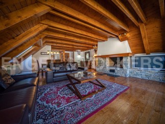 This stunning chalet boasts a spacious open-plan living area with exposed wooden beams, a cozy fireplace, and large windows offering ample natural light.