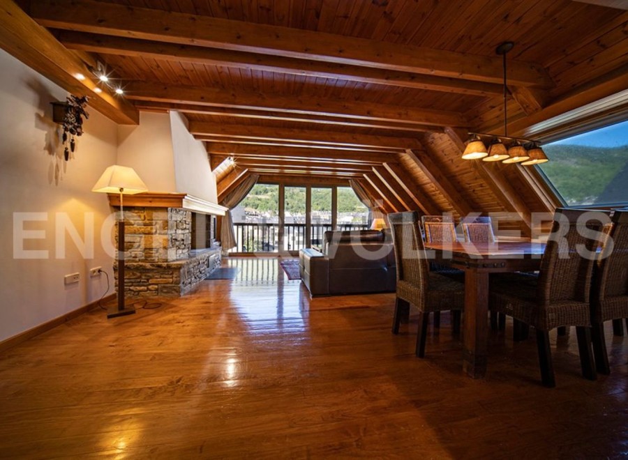 This stunning attic apartment boasts a spacious open-plan living area with hardwood floors, a cozy fireplace, and large windows offering breathtaking views.