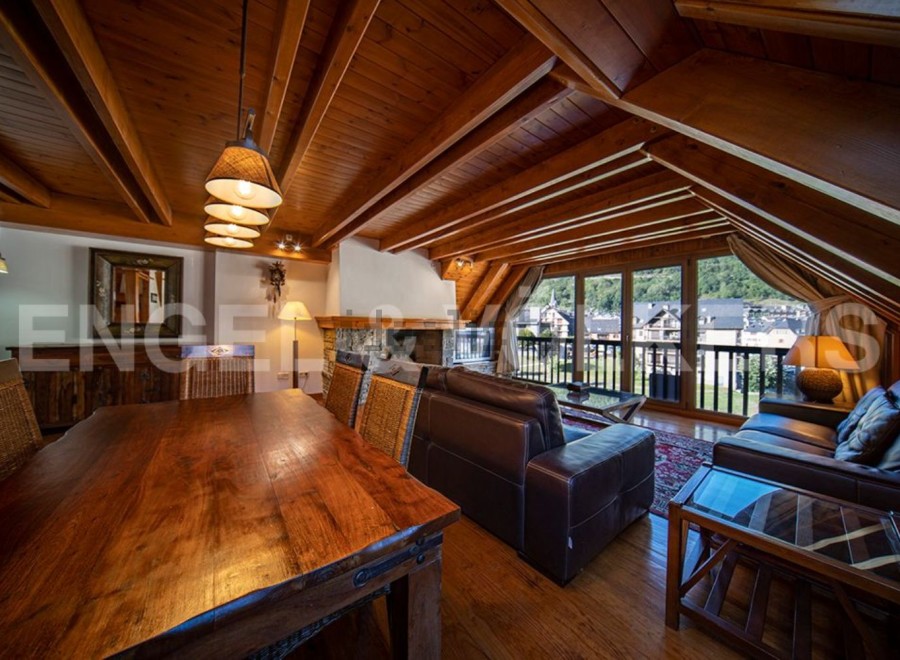 This stunning chalet boasts a spacious open-plan living area with a beautiful wooden ceiling and large windows offering breathtaking views.