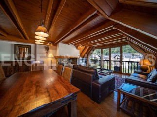 This stunning chalet boasts a spacious open-plan living area with a beautiful wooden ceiling and large windows offering breathtaking views.