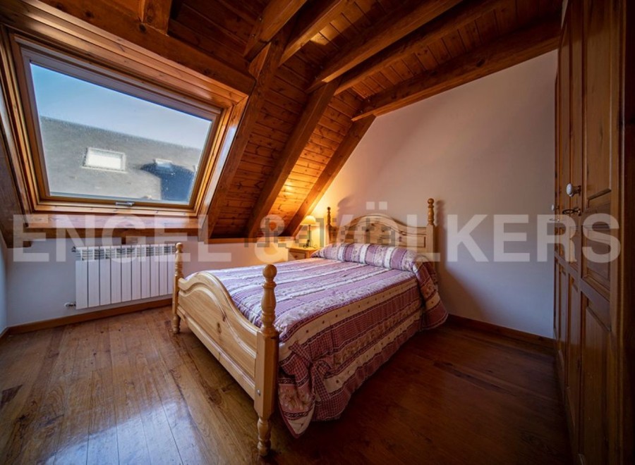 Charming attic bedroom with wooden beams, hardwood floors, and a large skylight offering ample natural light.