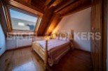 Charming attic bedroom with wooden beams, hardwood floors, and a large skylight offering ample natural light.