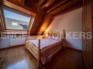 Charming attic bedroom with wooden beams, hardwood floors, and a large skylight offering ample natural light.