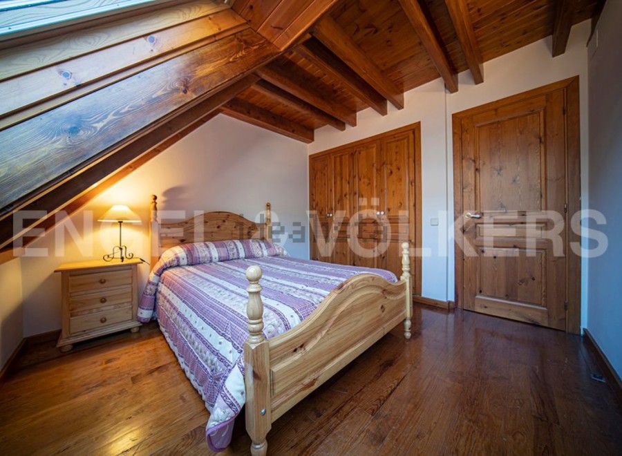 Charming attic bedroom with wooden beams, skylight, and hardwood floors.