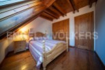 Charming attic bedroom with wooden beams, skylight, and hardwood floors.