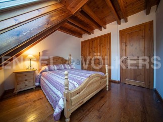 Charming attic bedroom with wooden beams, skylight, and hardwood floors.