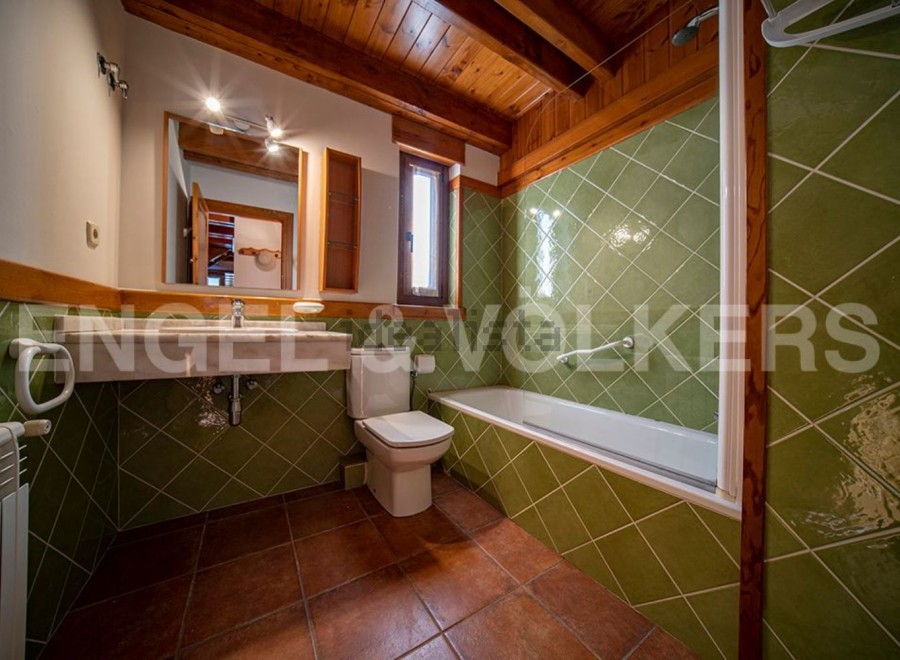 Charming bathroom with green tile and wooden accents.