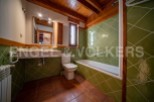 Charming bathroom with green tile and wooden accents.