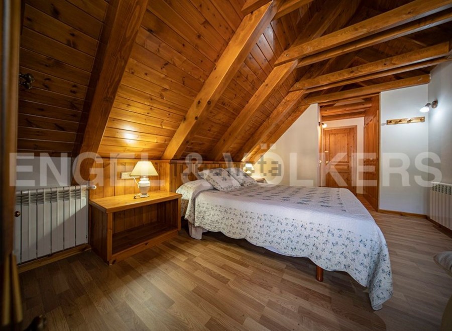 Cozy chalet bedroom with wooden beams and flooring.