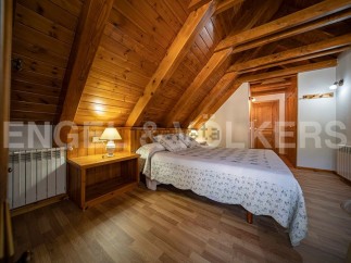 Cozy chalet bedroom with wooden beams and flooring.