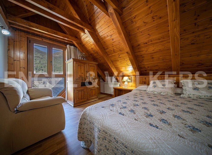Cozy attic bedroom with wooden beams and mountain views.