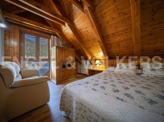 Cozy attic bedroom with wooden beams and mountain views.