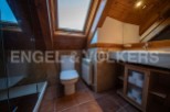 Charming attic bathroom with skylight, wooden beams, and a modern toilet and sink.
