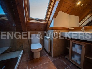 Charming attic bathroom with skylight, wooden beams, and a modern toilet and sink.