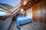 Cozy attic bedroom with wooden beams and skylights offering stunning mountain views.