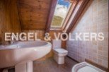 Charming attic bathroom with wooden beams, skylight, and tiled walls.
