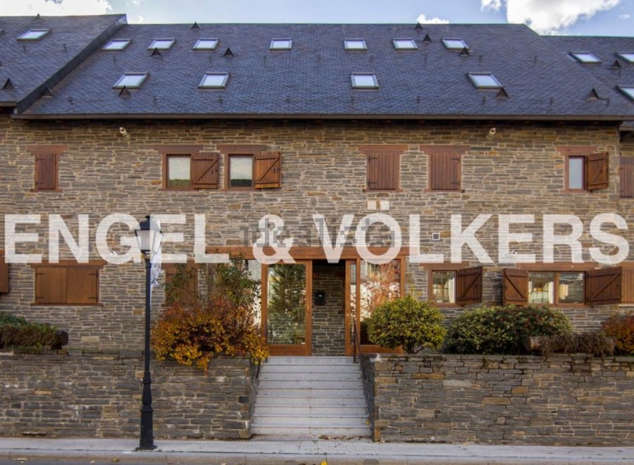 This stunning stone building boasts a charming facade with multiple dormers and wooden shutters.