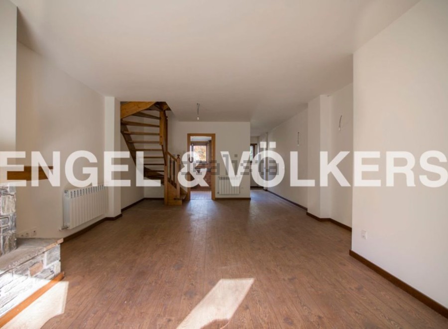 Spacious open-plan living area with wooden flooring and a stunning spiral staircase.