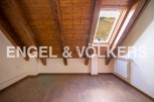 Charming attic room with wooden beams and skylight offering scenic views.