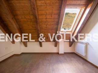 Charming attic room with wooden beams and skylight offering scenic views.