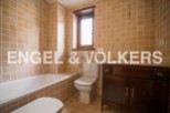 This charming bathroom boasts a classic design with light beige tiles, a built-in bathtub, and a wooden vanity.