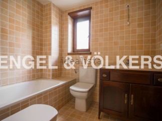 This charming bathroom boasts a classic design with light beige tiles, a built-in bathtub, and a wooden vanity.