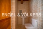 This charming bathroom boasts a modern toilet and pedestal sink, complemented by warm, earthy-toned tiles.