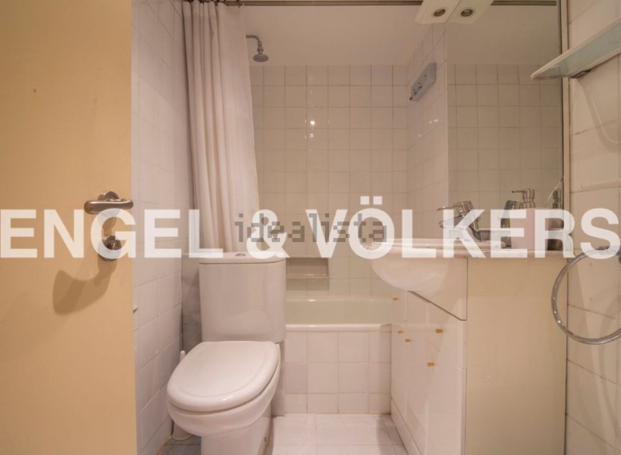 This charming bathroom boasts a classic white tile design, complemented by a shower/tub combo and modern vanity.