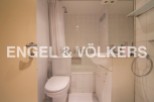 This charming bathroom boasts a classic white tile design, complemented by a shower/tub combo and modern vanity.
