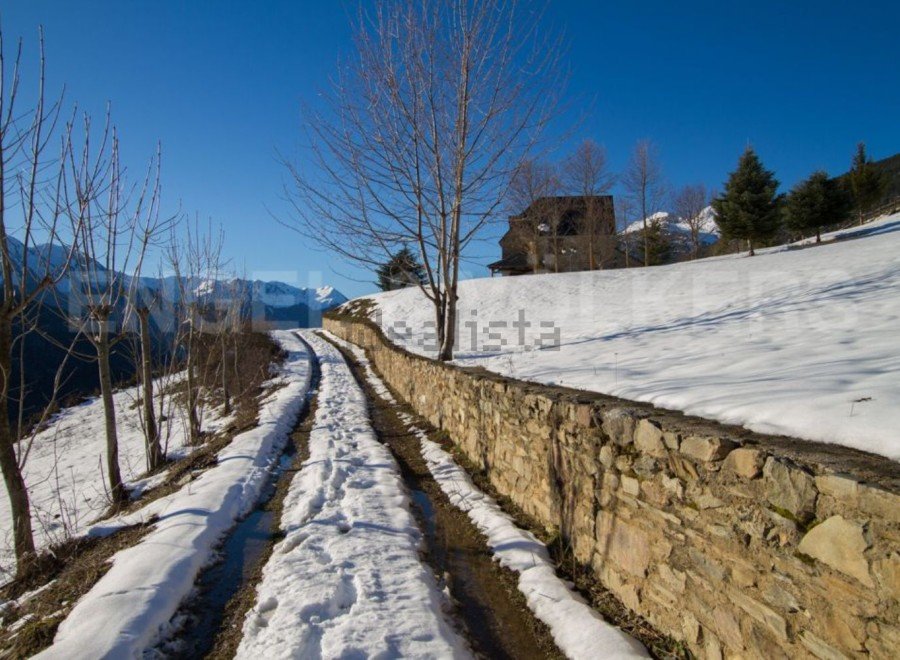 Mountainside property with stunning views and a rustic stone wall.
