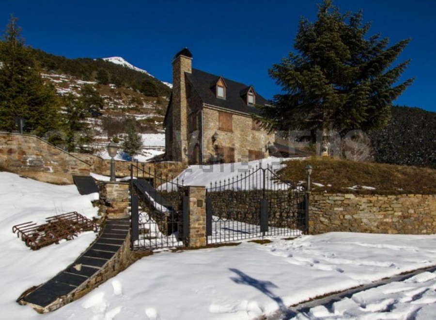 Discover a charming stone house nestled in a snowy mountain landscape.