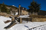 Discover a charming stone house nestled in a snowy mountain landscape.