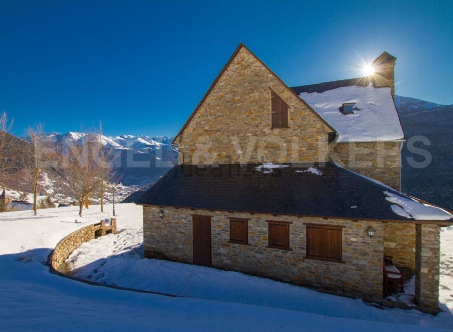 Discover a charming stone house nestled in a snowy mountain landscape.