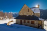 Discover a charming stone house nestled in a snowy mountain landscape.