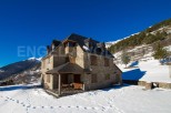 Discover a stunning stone house nestled in a picturesque snowy landscape.