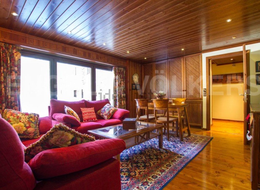 Discover the charm of this inviting living space, featuring a cozy red sofa and a warm wooden interior.