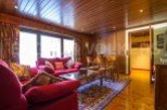 Discover the charm of this inviting living space, featuring a cozy red sofa and a warm wooden interior.