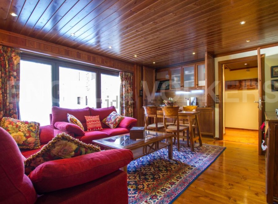 Discover the charm of this inviting living space, featuring a cozy red sofa and a warm wooden interior.