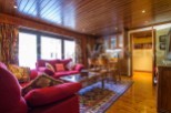 Discover the charm of this inviting living space, featuring a cozy red sofa and a warm wooden interior.
