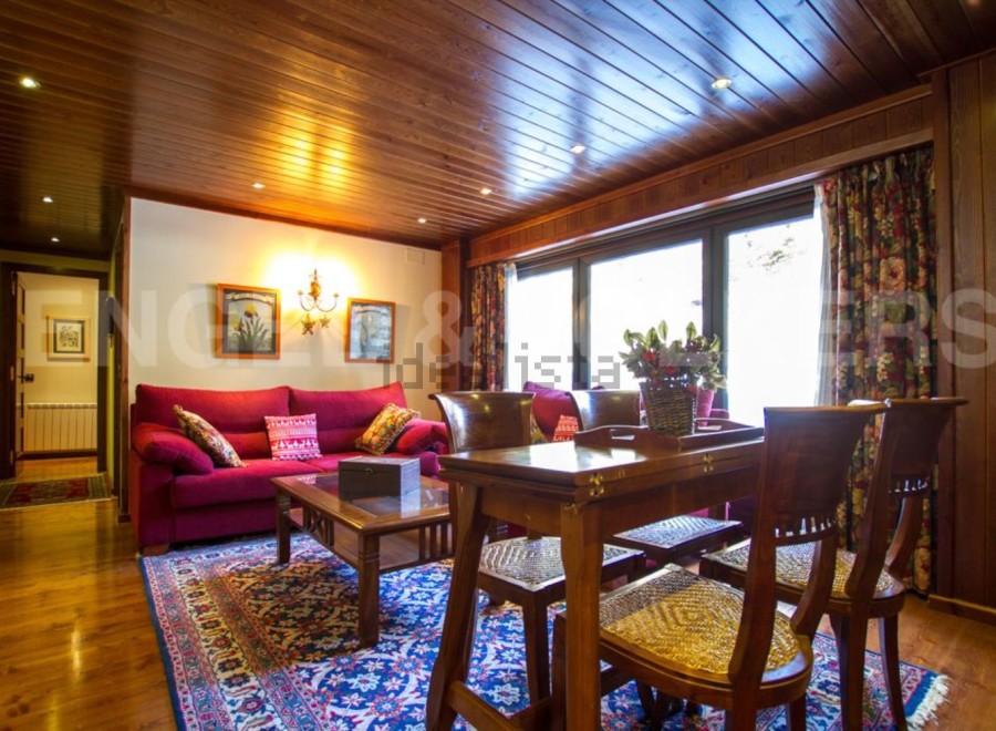 Discover the charm of this inviting living space, featuring a cozy red sofa and a stylish wooden dining set.