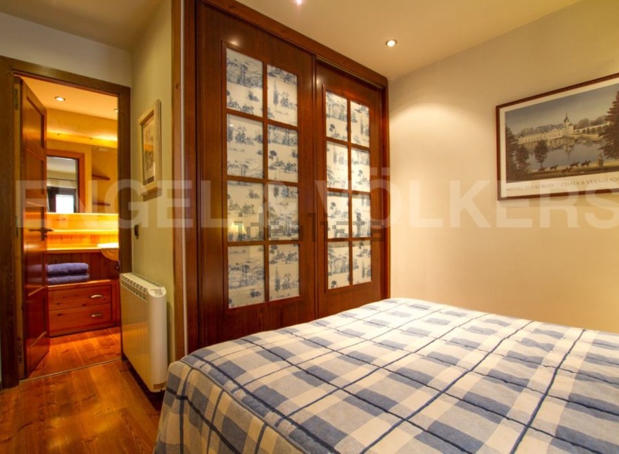 Discover the charm of this cozy bedroom, featuring elegant wooden doors and a stylish bedspread.