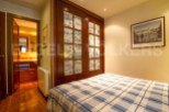 Discover the charm of this cozy bedroom, featuring elegant wooden doors and a stylish bedspread.