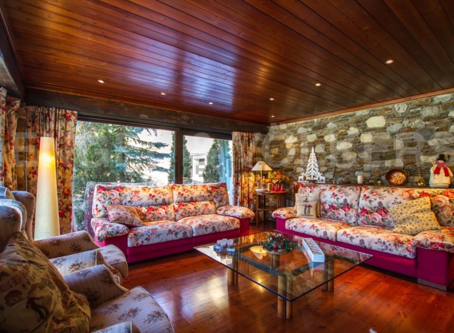 Step into a cozy living room with a stunning stone wall and a warm wooden ceiling.