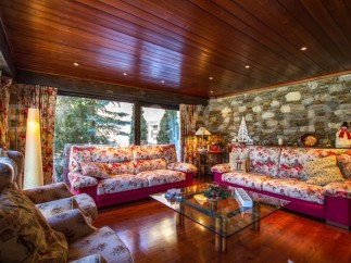 Step into a cozy living room with a stunning stone wall and a warm wooden ceiling.