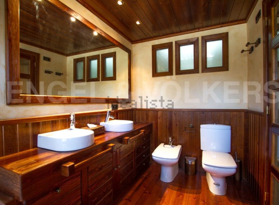 Discover the rustic charm of this bathroom, featuring a stunning wooden vanity with dual sinks.